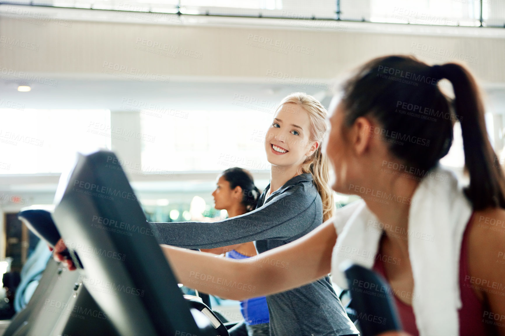 Buy stock photo Cropped shot of attractive young women working out on treadmills at the gym