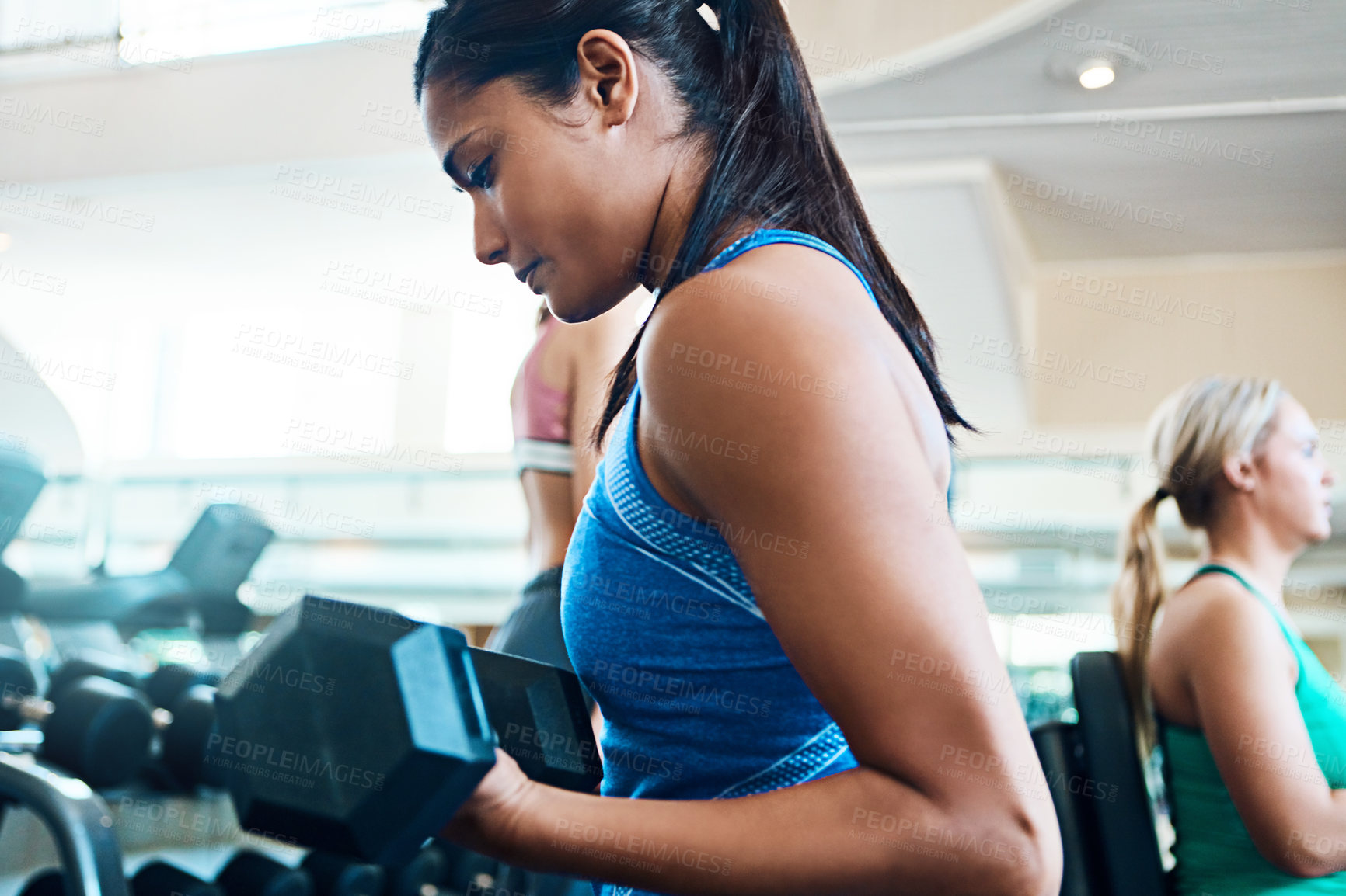 Buy stock photo Cropped shot of attractive young women working out with dumbbells at the gym
