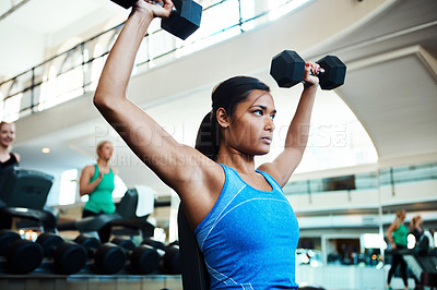 Buy stock photo Cropped shot of an attractive young woman working out with dumbbells at the gym