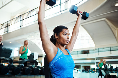 Buy stock photo Cropped shot of an attractive young woman working out with dumbbells at the gym