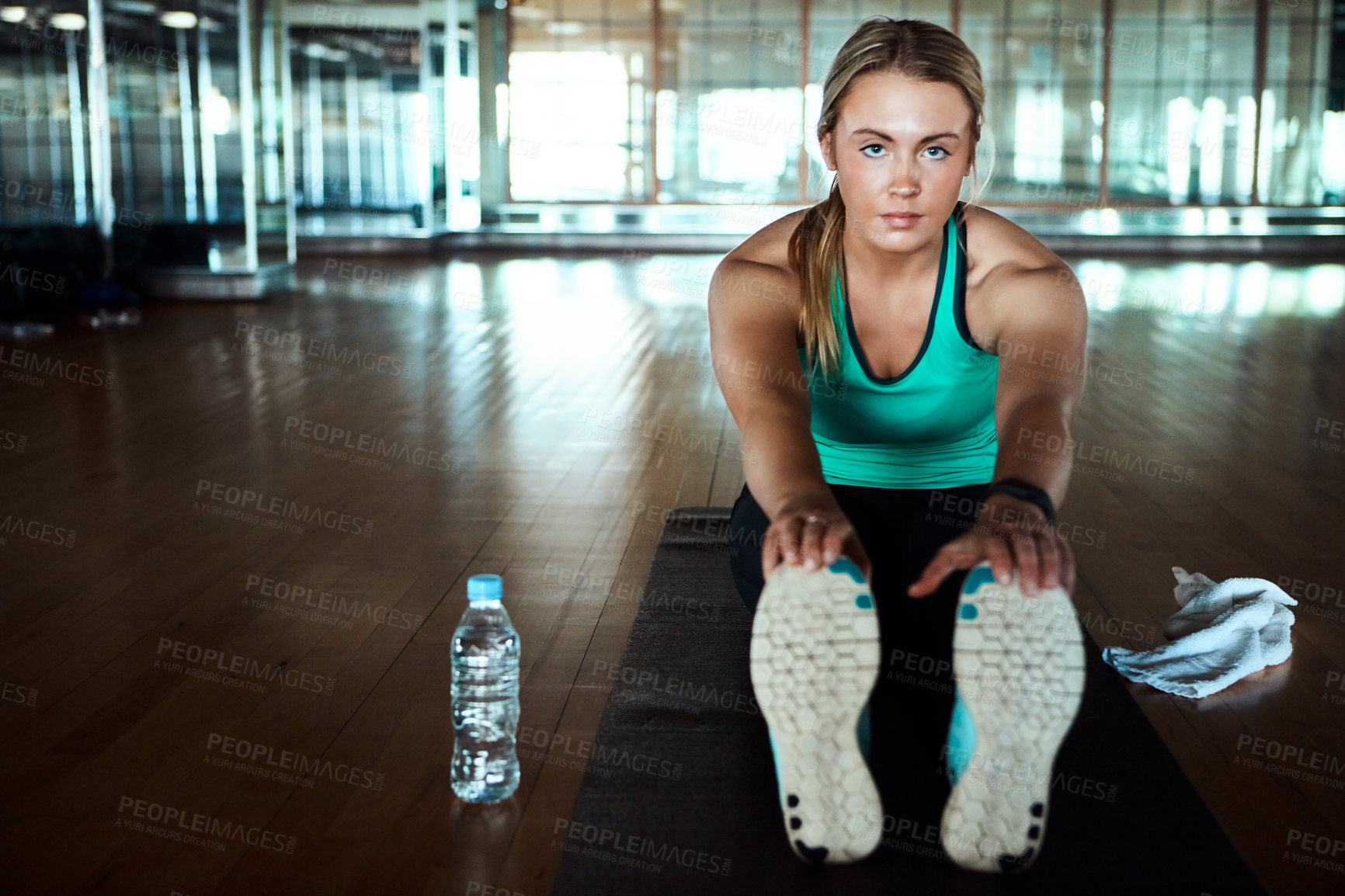 Buy stock photo Shot of an attractive young woman going through her warmup routine in the gym