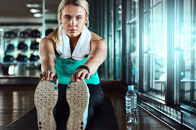 Buy stock photo Shot of an attractive young woman going through her warmup routine in the gym