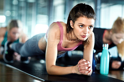 Buy stock photo Shot of an attractive young woman planking as part of her workout in the gym