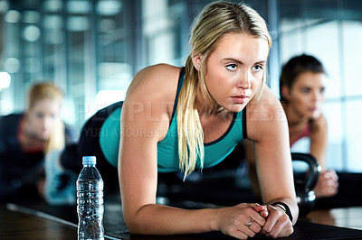 Buy stock photo Shot of an attractive young woman planking as part of her workout in the gym