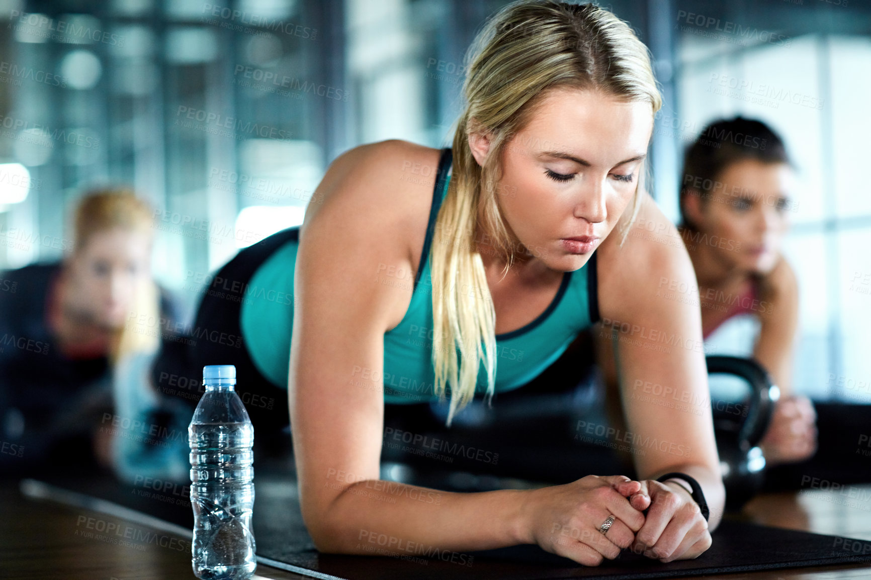 Buy stock photo Shot of an attractive young woman planking as part of her workout in the gym