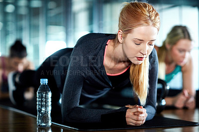 Buy stock photo Shot of an attractive young woman planking as part of her workout in the gym