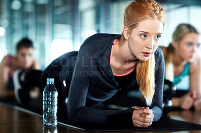 Buy stock photo Shot of an attractive young woman planking as part of her workout in the gym