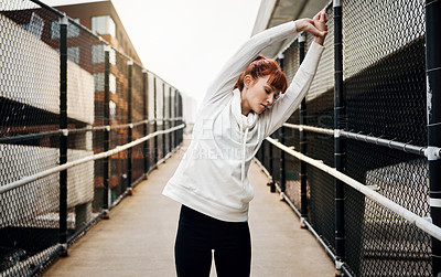 Buy stock photo Cropped shot of an attractive young woman stretching before her run in the city