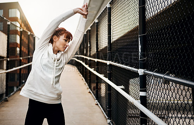 Buy stock photo Cropped shot of an attractive young woman stretching before her run in the city