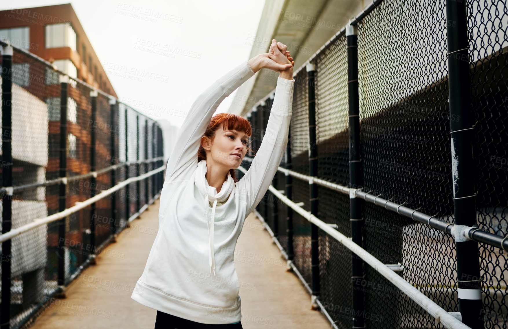 Buy stock photo Cropped shot of an attractive young woman stretching before her run in the city