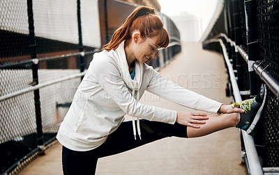 Buy stock photo Cropped shot of an attractive young woman stretching before her run in the city