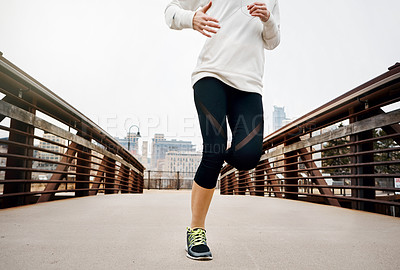 Buy stock photo Shot of an unrecognisable young woman listening to music while running in the city