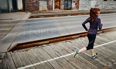 Buy stock photo Rear view shot of a sporty young woman running in the city