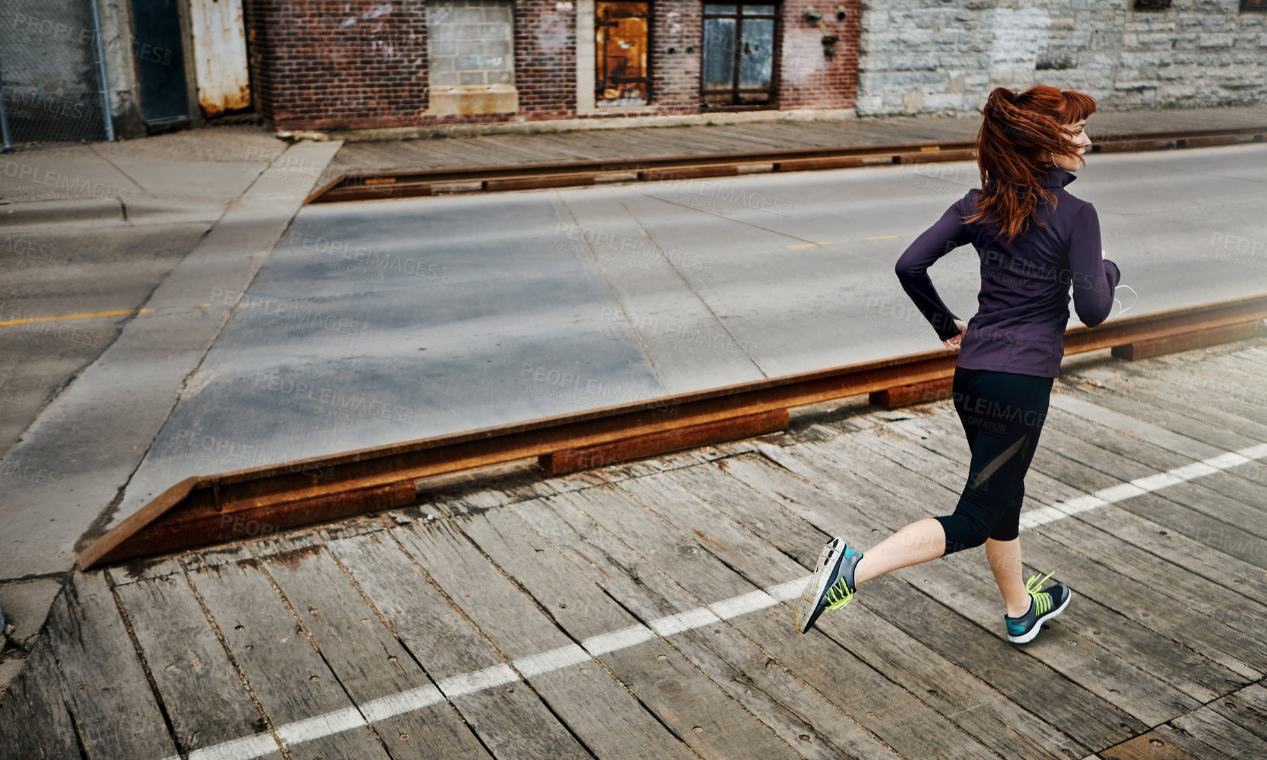 Buy stock photo Rear view shot of a sporty young woman running in the city