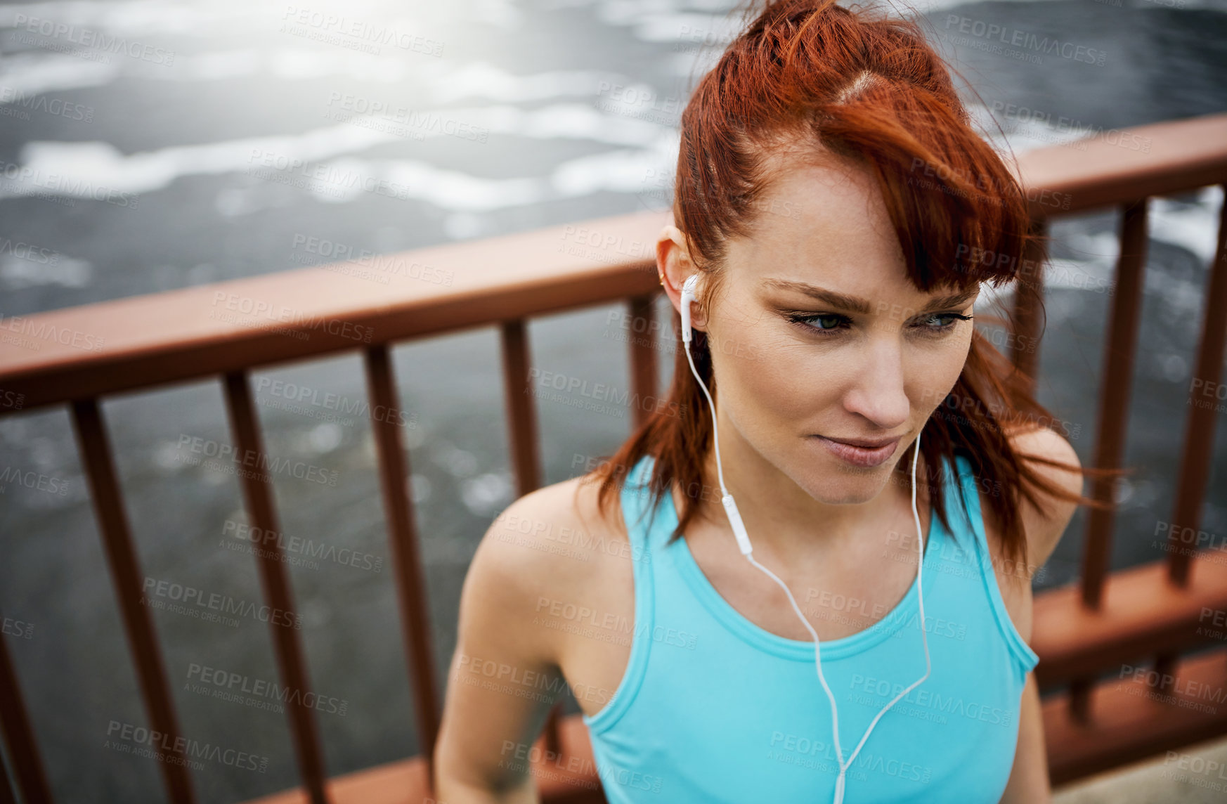 Buy stock photo Shot of a sporty young woman listening to music while out for a run in the city