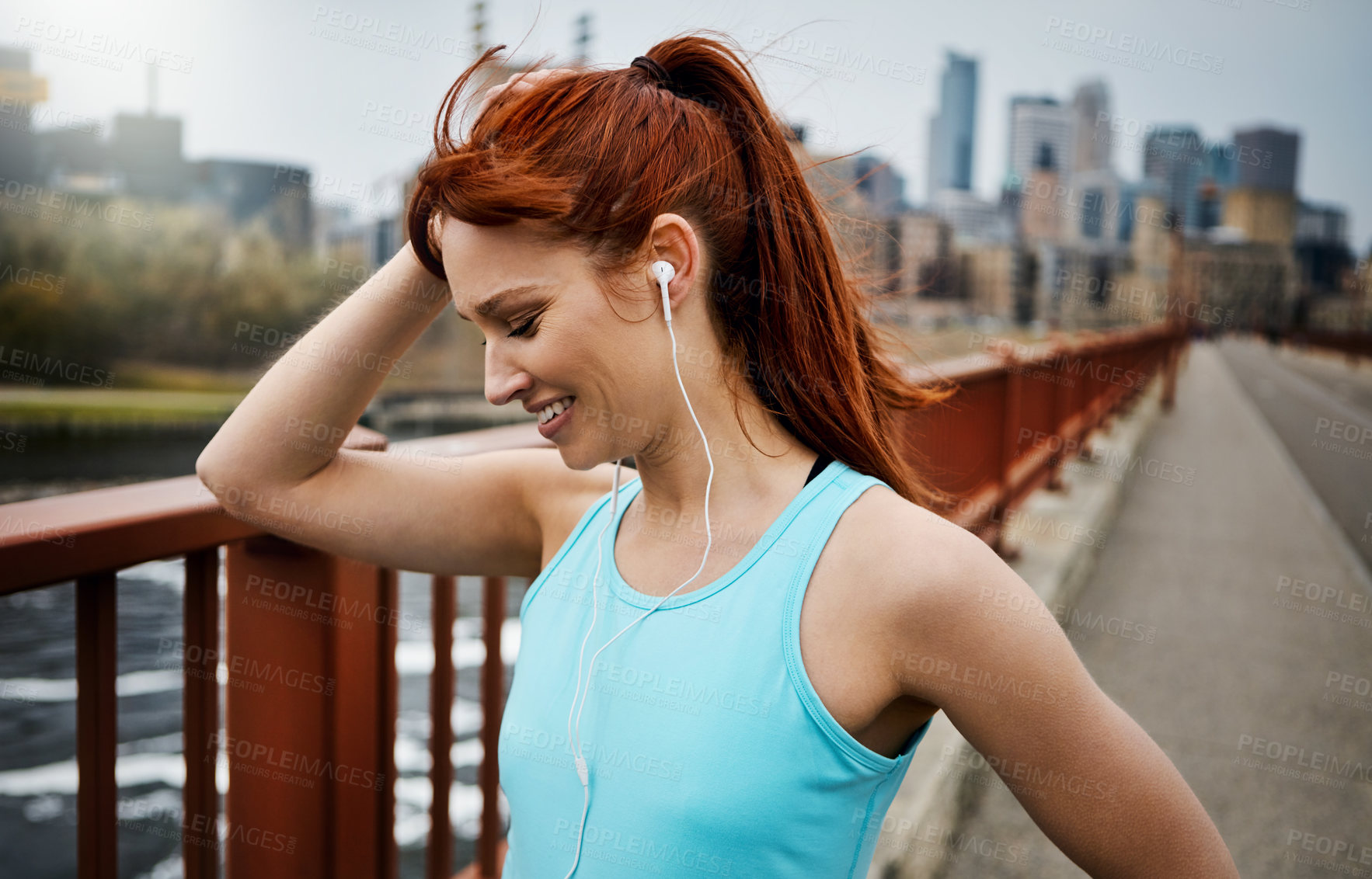 Buy stock photo Shot of a sporty young woman listening to music while out for a run in the city