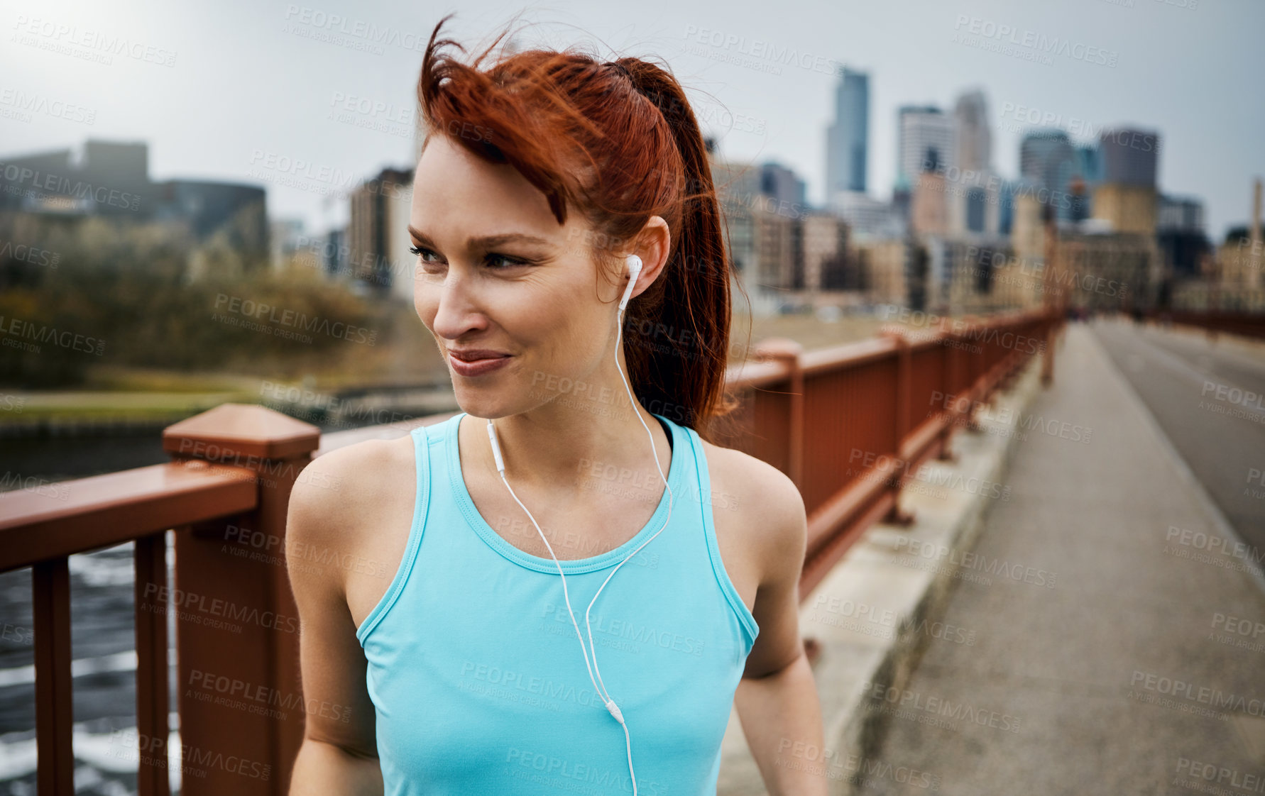 Buy stock photo Shot of a sporty young woman listening to music while out for a run in the city