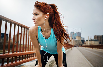 Buy stock photo Shot of a sporty young woman taking a break while running in the city