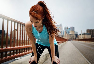 Buy stock photo Shot of a sporty young woman taking a break while running in the city