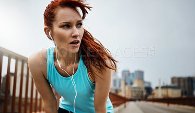 Buy stock photo Shot of a sporty young woman taking a break while running in the city