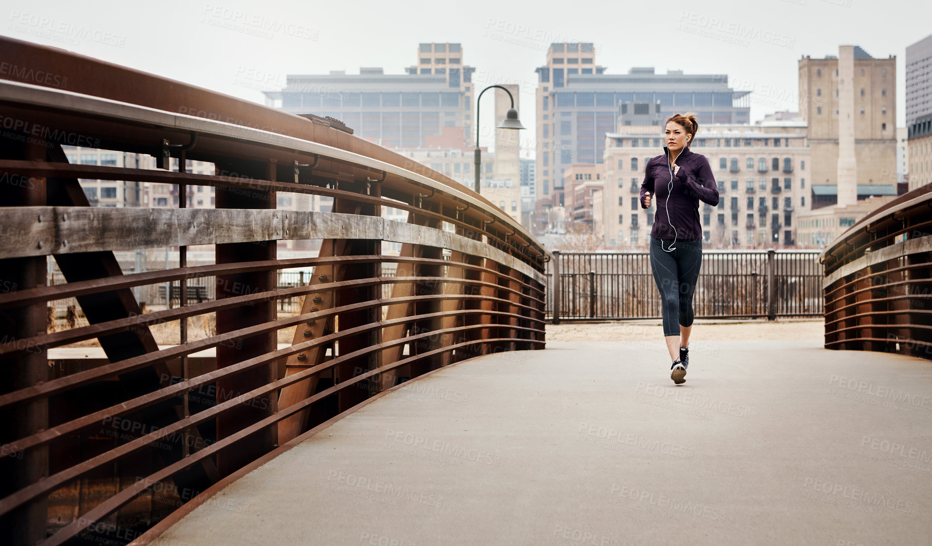 Buy stock photo Full length shot of an attractive young woman listening to music while running through the city