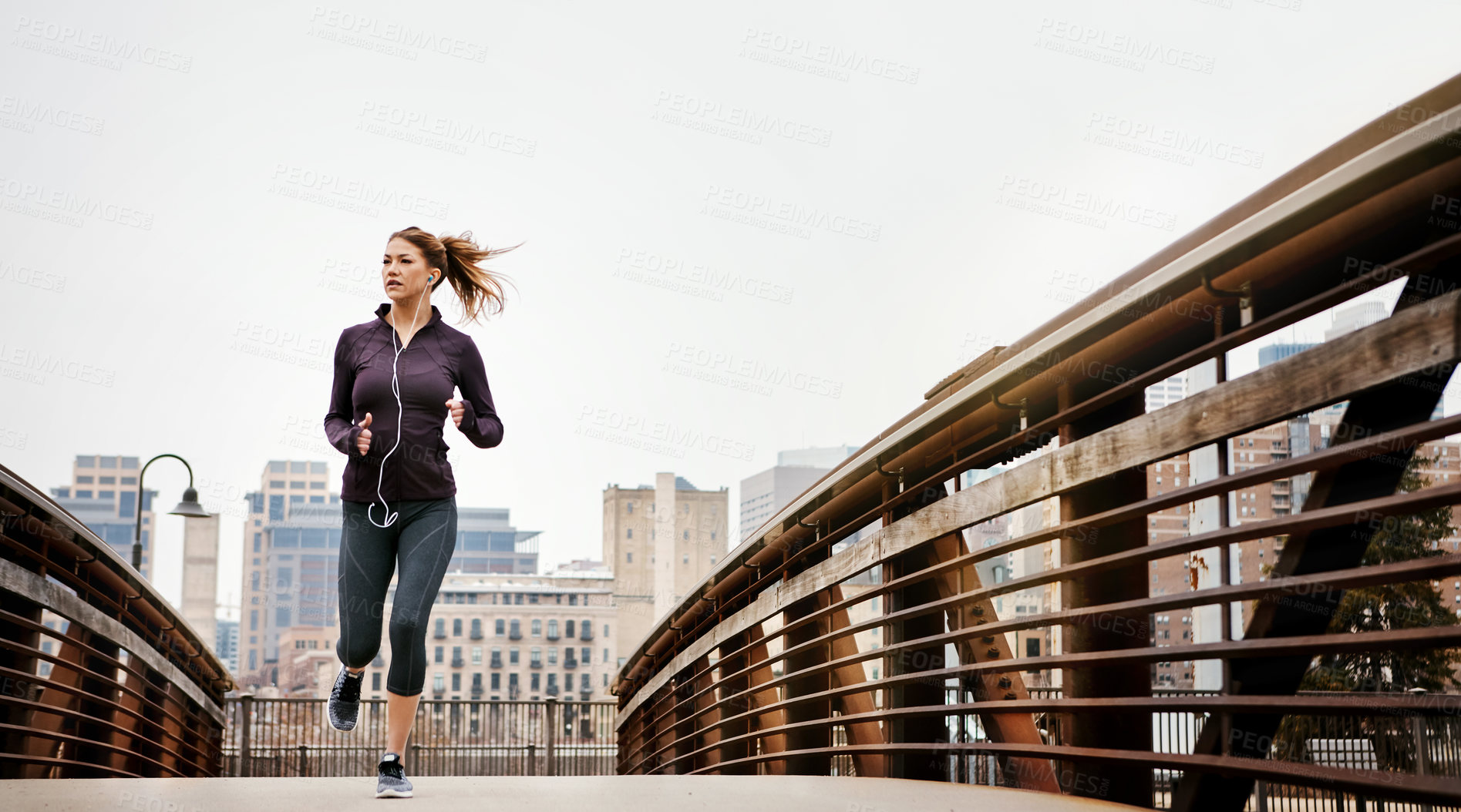 Buy stock photo Full length shot of an attractive young woman listening to music while running through the city