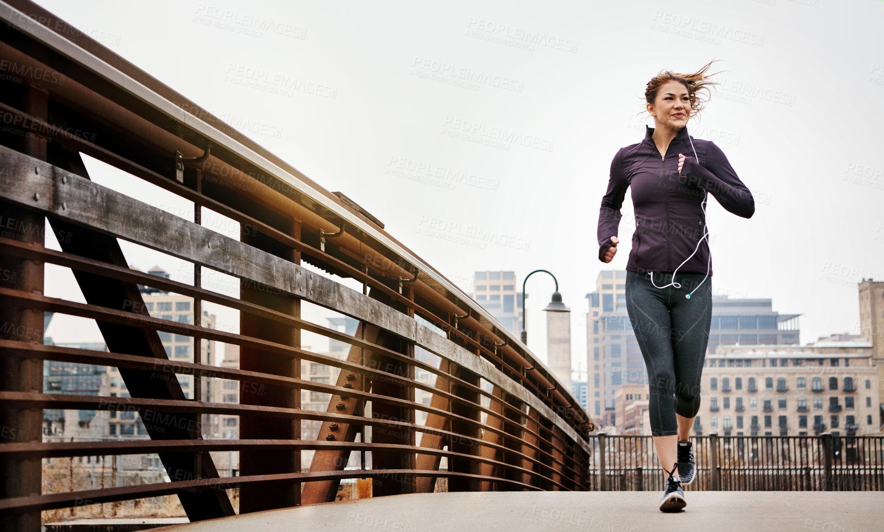 Buy stock photo Full length shot of an attractive young woman listening to music while running through the city