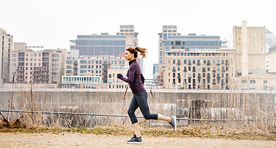 Buy stock photo Full length shot of an attractive young woman taking a run through the city