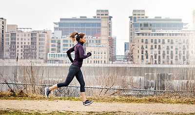 Buy stock photo Full length shot of an attractive young woman taking a run through the city