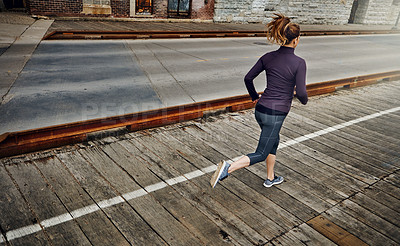 Buy stock photo Rearview shot of an unrecognizable young woman running through the city