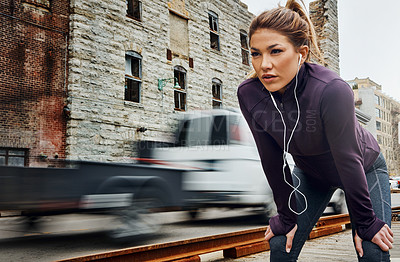 Buy stock photo Cropped shot of an attractive young woman listening to music while running through the city