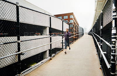 Buy stock photo Full length shot of an attractive young woman listening to music while running through the city