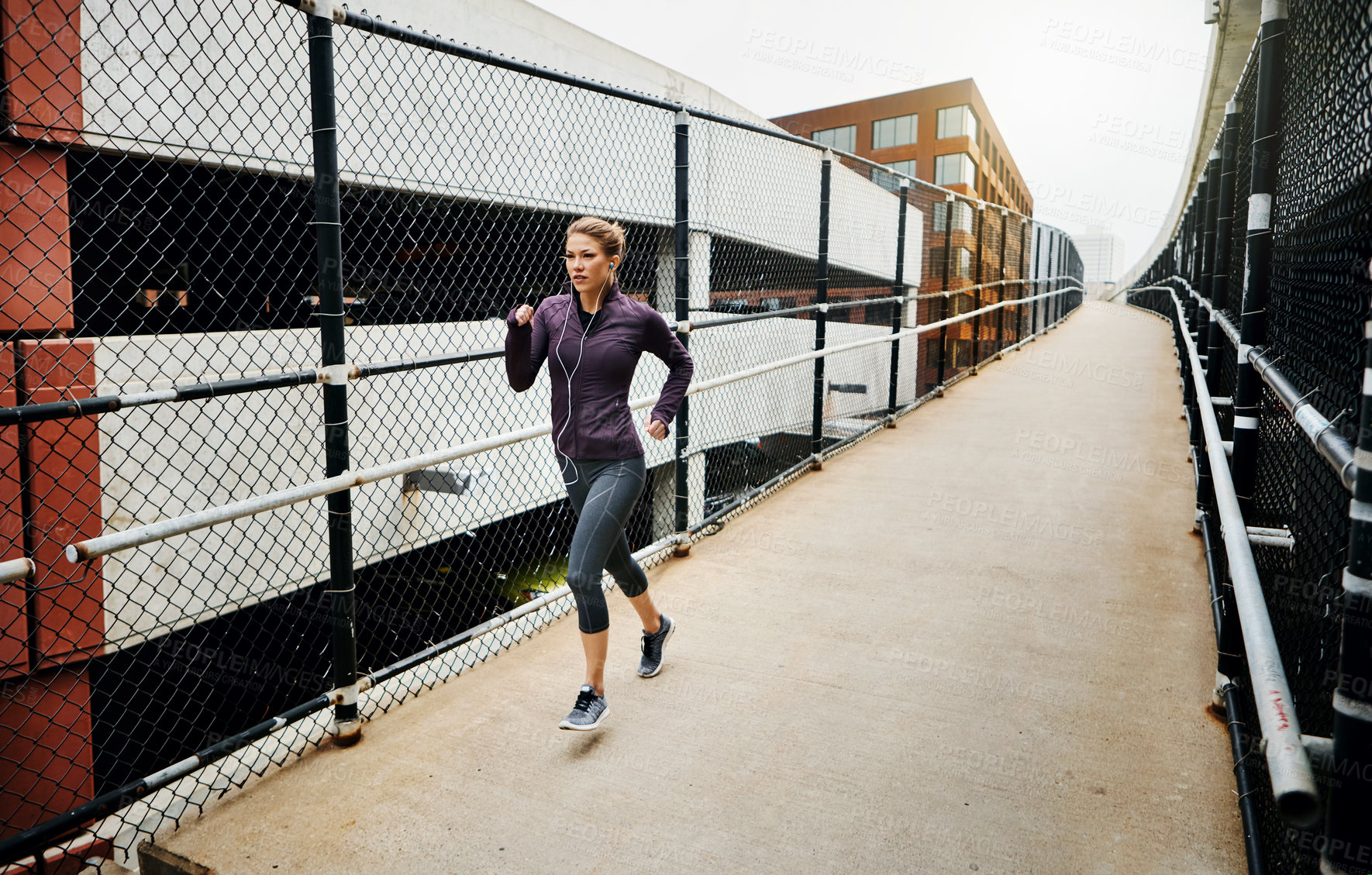 Buy stock photo Full length shot of an attractive young woman listening to music while running through the city