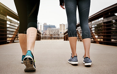 Buy stock photo Rearview shot of two unrecognizable young women running through the city