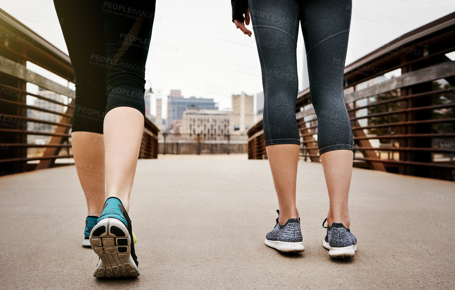 Buy stock photo Rearview shot of two unrecognizable young women running through the city