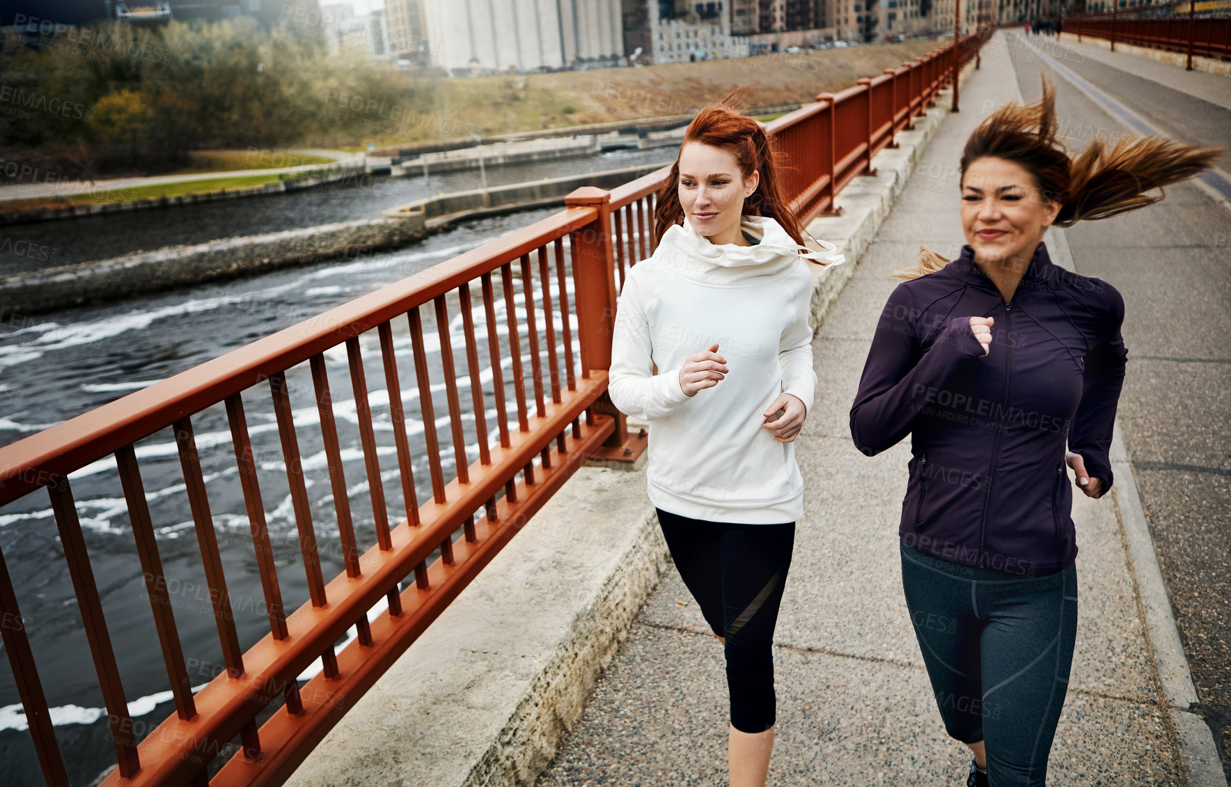 Buy stock photo Cropped shot of two attractive young women running through the city