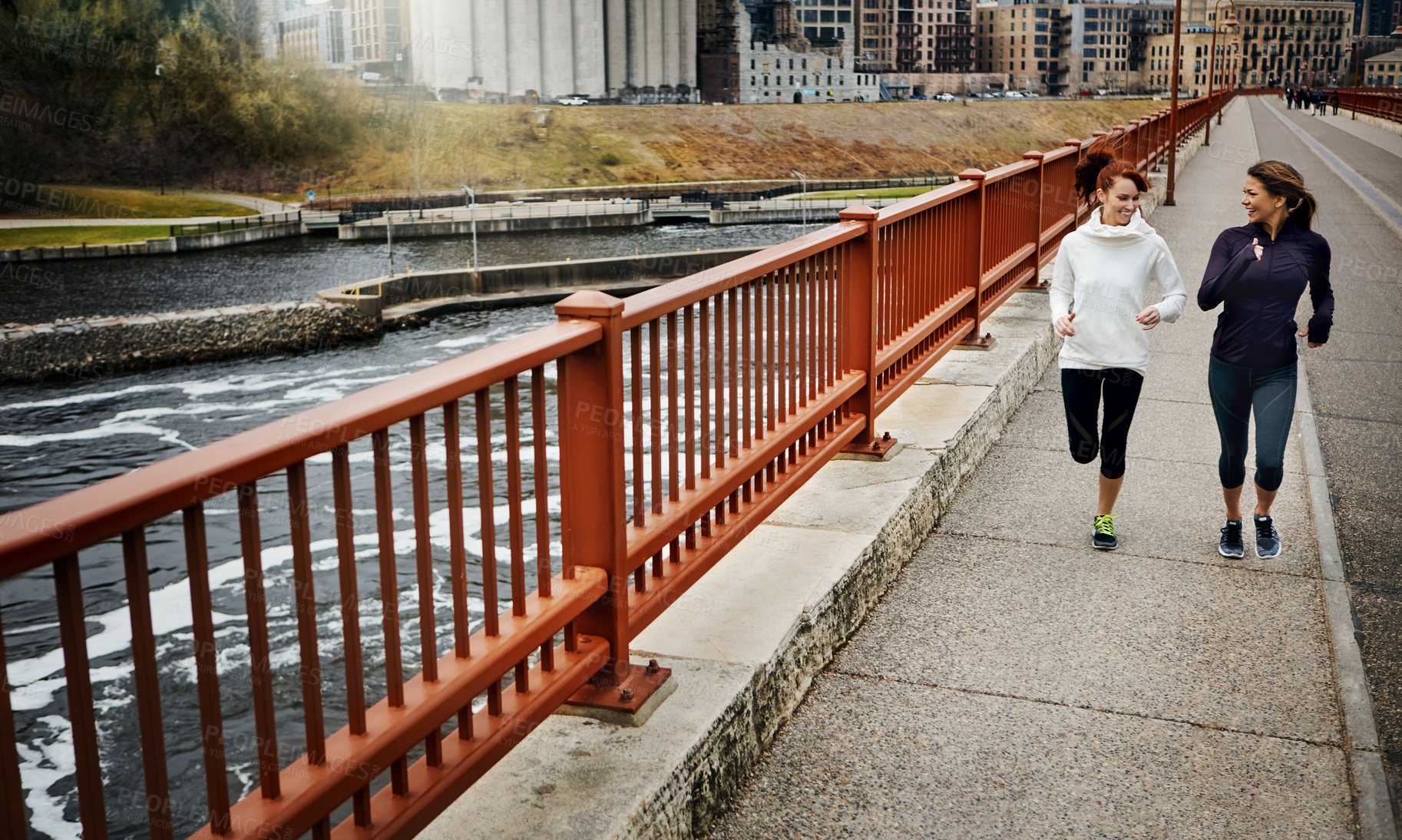 Buy stock photo Full length shot of two attractive young women running through the city