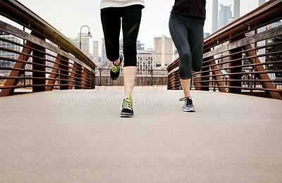 Buy stock photo Cropped shot of two unrecognizable young women running through the city