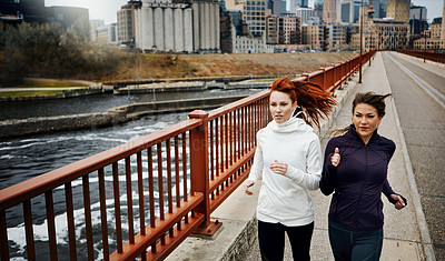 Buy stock photo Cropped shot of two attractive young women running through the city