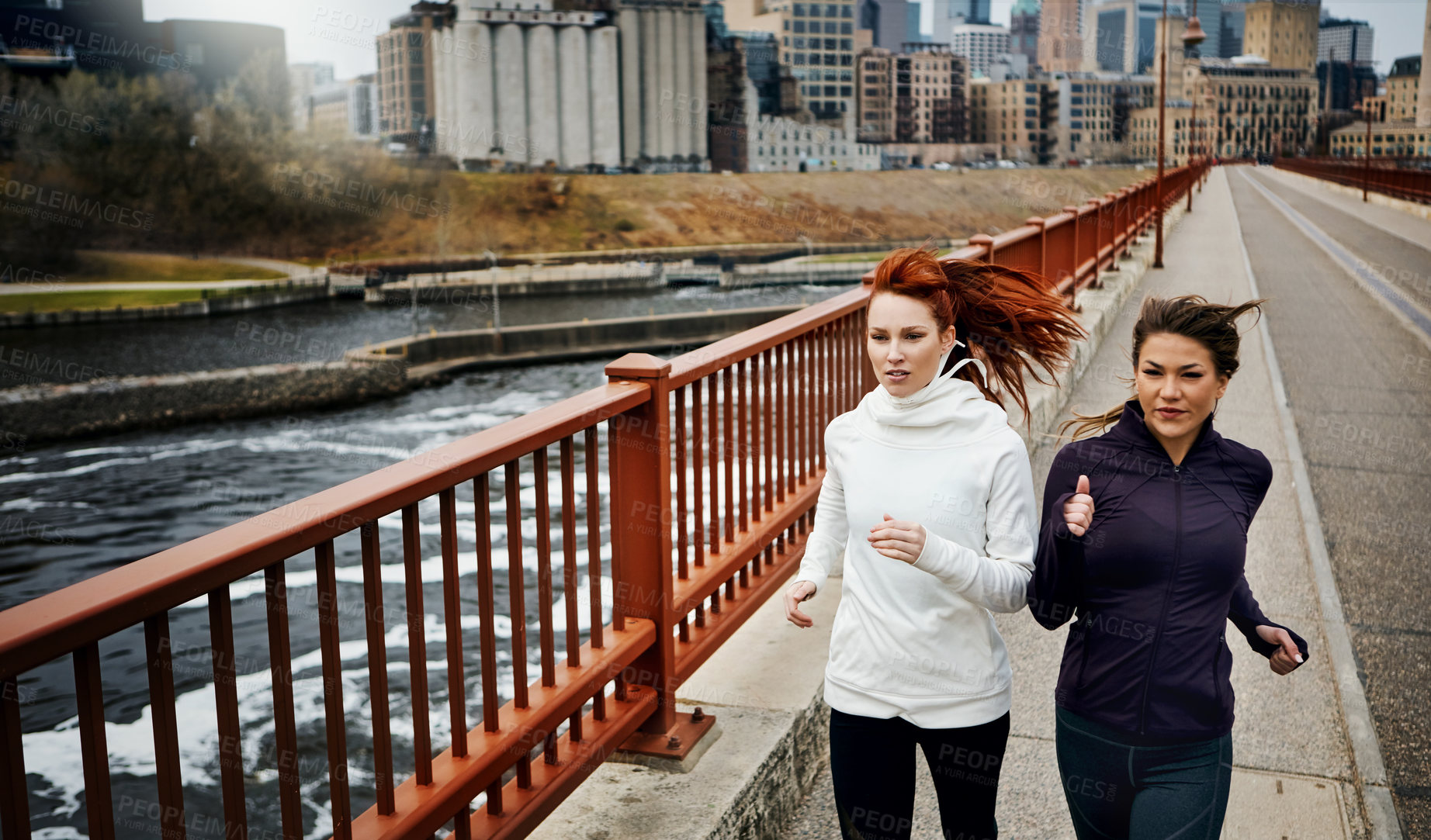 Buy stock photo Cropped shot of two attractive young women running through the city