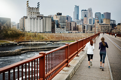 Buy stock photo Rearview shot of two unrecognizable young women running through the city