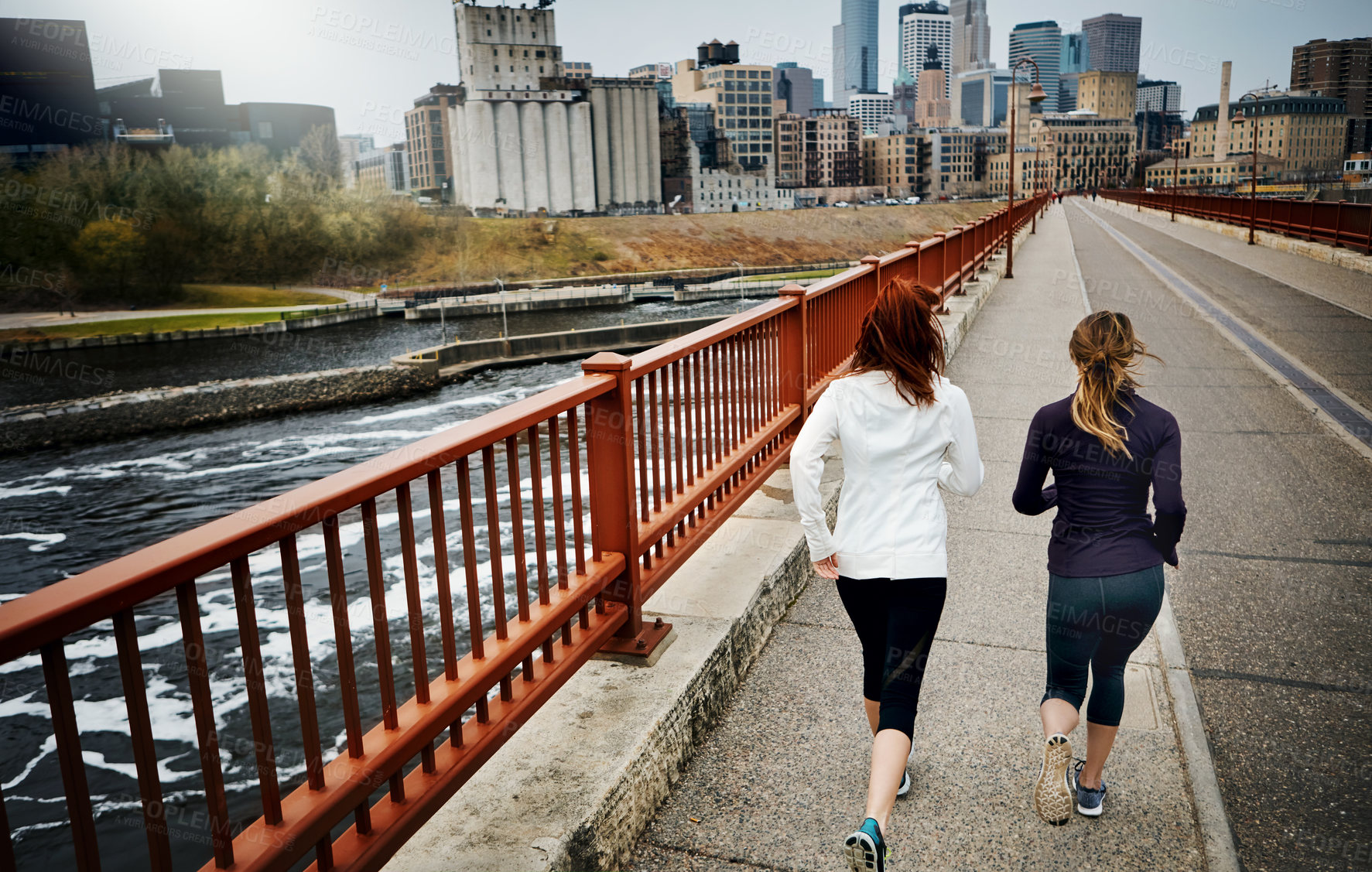 Buy stock photo Rearview shot of two unrecognizable young women running through the city