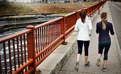 Buy stock photo Rearview shot of two unrecognizable young women running through the city