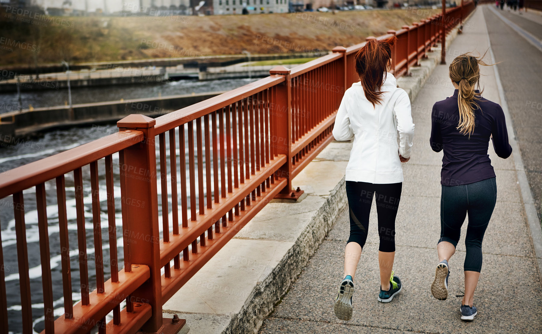 Buy stock photo Rearview shot of two unrecognizable young women running through the city