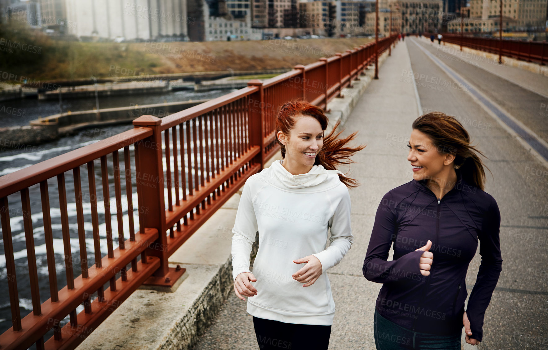 Buy stock photo Cropped shot of two attractive young women running through the city