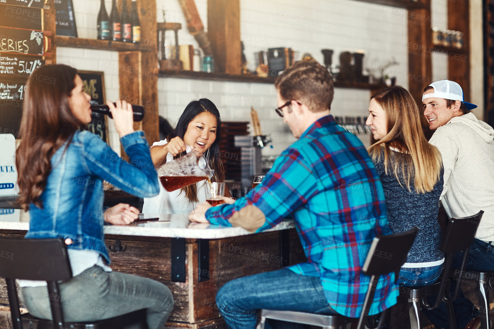 Buy stock photo Shot of a young woman serving drinks in a bar 