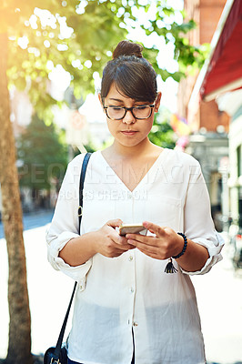 Buy stock photo Shot of a young woman using a mobile phone while out in the city
