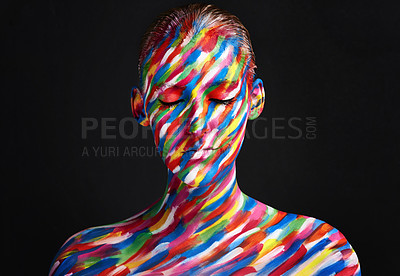 Buy stock photo Studio shot of a young woman posing with brightly colored paint on her face against a black background