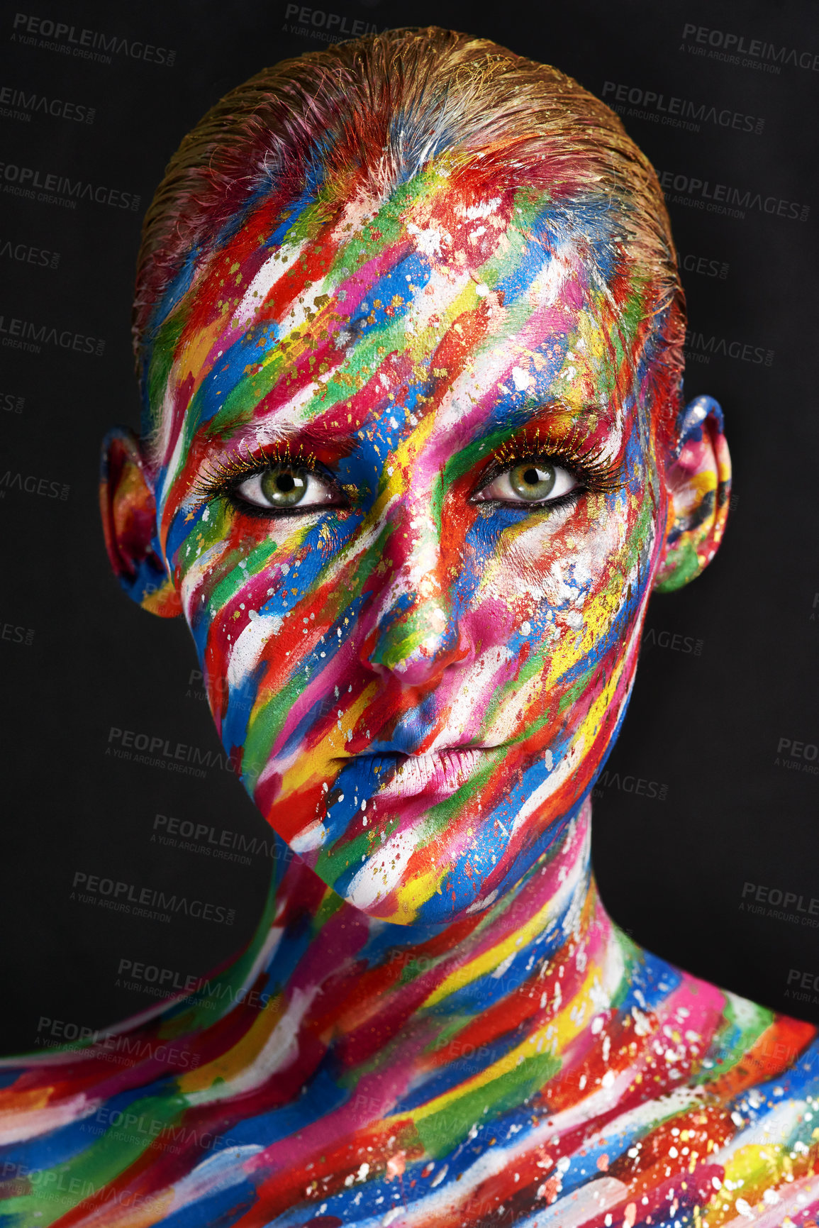 Buy stock photo Studio shot of a young woman posing with brightly colored paint on her face against a black background