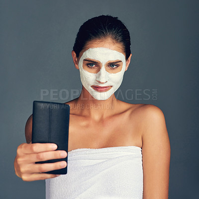 Buy stock photo Skincare, woman and selfie with face mask in studio for beauty, self care and cosmetics on gray background. Female person, serious and cream for facial, transformation and treatment for social media